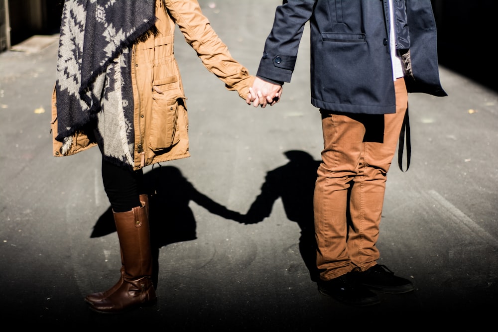 man and woman standing while holding hands at daytime