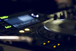 Close-up of DJ equipment with glowing buttons and a marine blue backdrop.