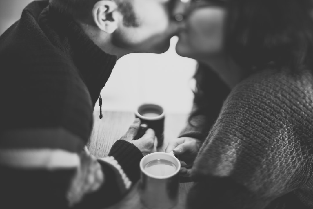 grayscale photography of a man kissing a woman