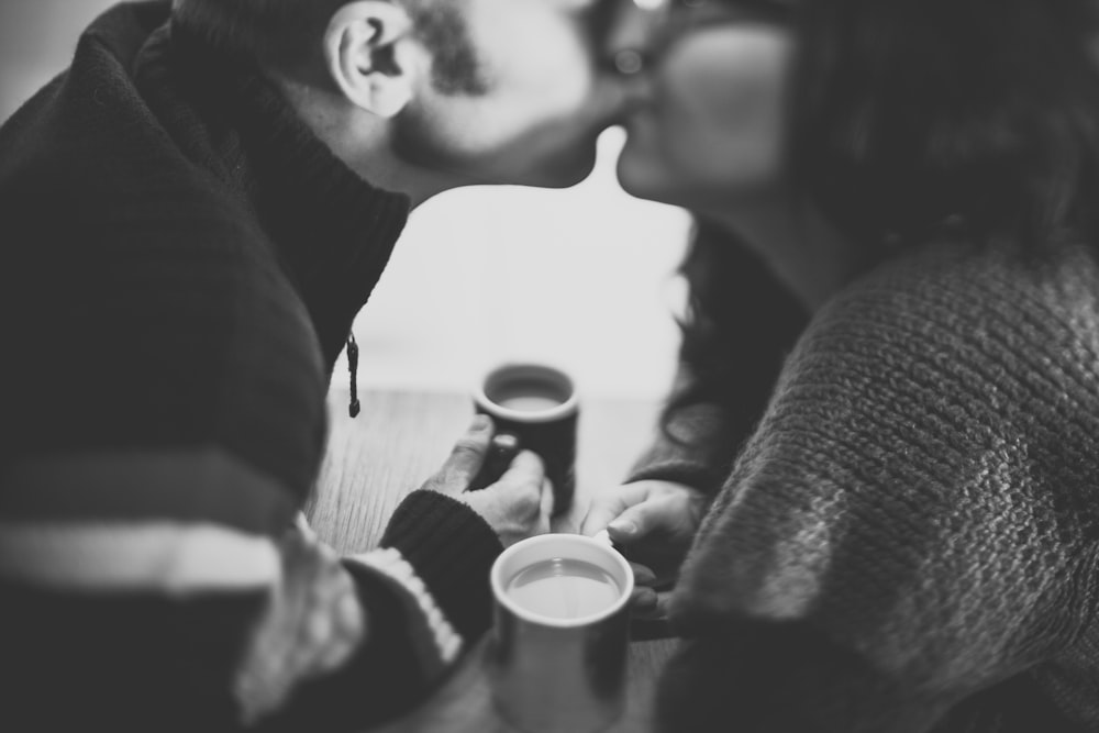 Photographie en niveaux de gris d’un homme embrassant une femme