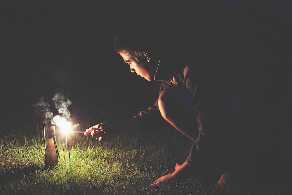 man crouching holding sparkler