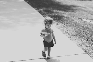 A candid shot of a child playing in sun-dappled park surroundings.