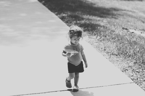 A candid shot of a child playing in sun-dappled park surroundings.