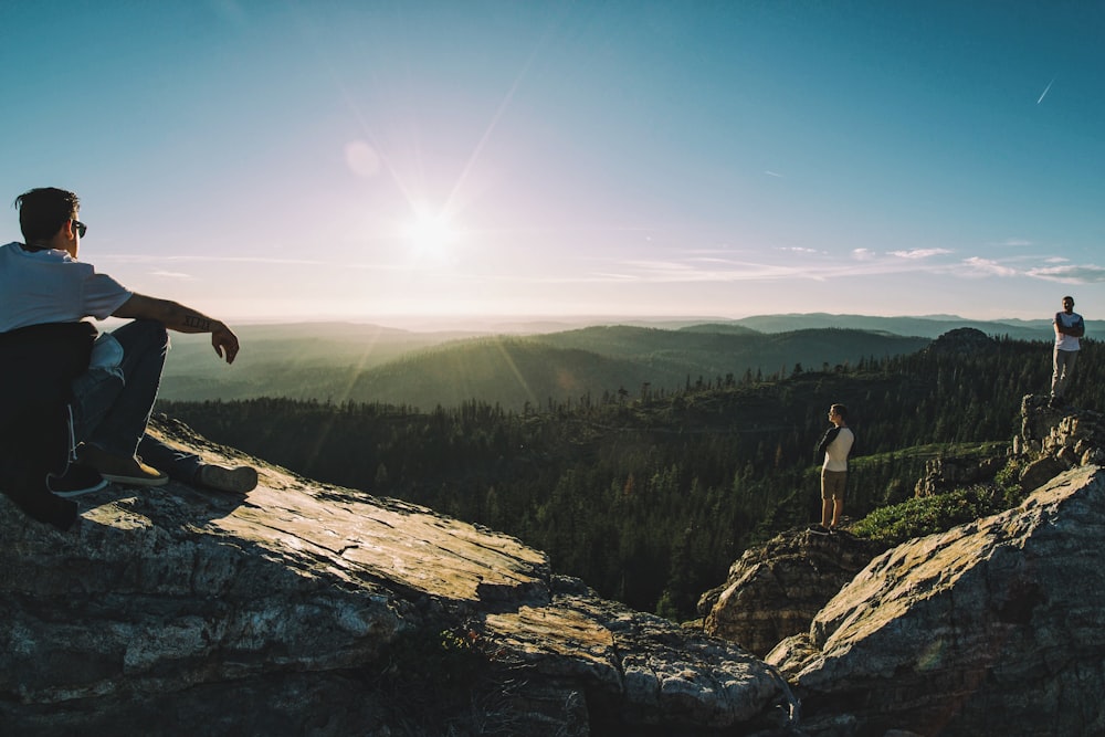 man sitting on cliff facing trees