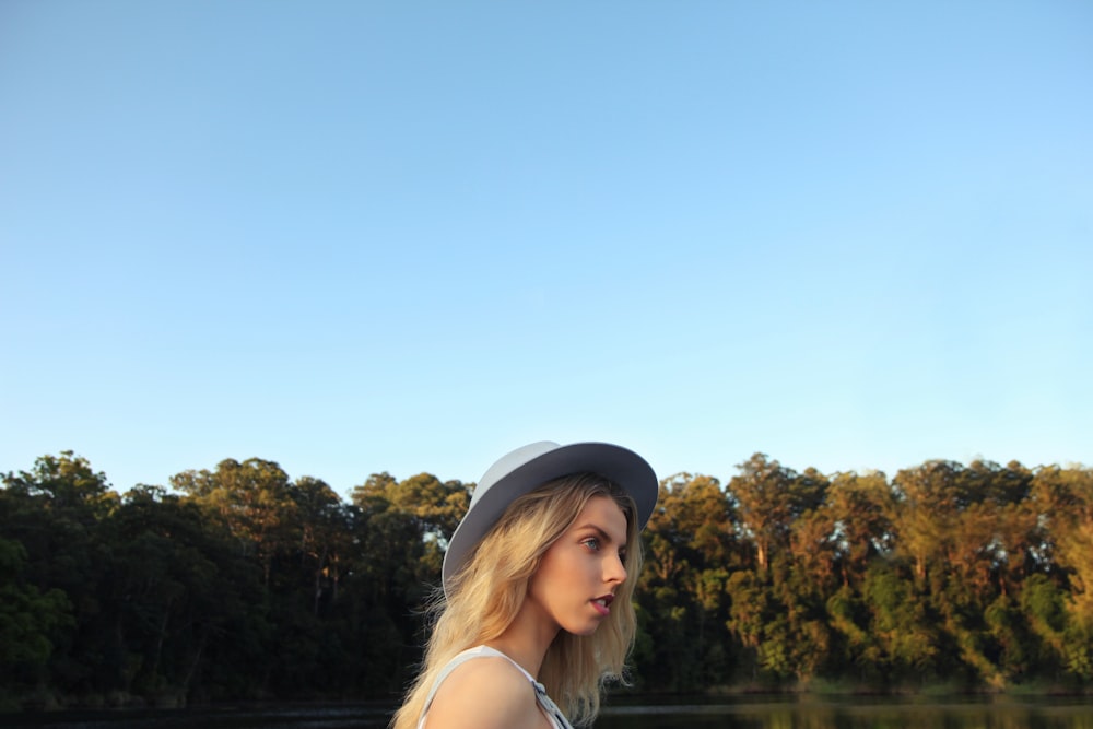 woman standing near body of water and trees