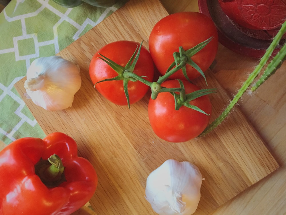 drei Tomaten neben Knoblauch