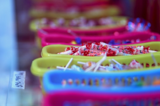 Photo of colorful assorted sweets and chocolates neatly arranged in baskets at a wholesale supplier warehouse.