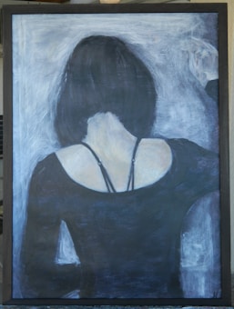 A painting depicts the back view of a person with short, dark hair, and a black top with thin straps. The figure stands against a textured background with lighter shades, creating contrast.