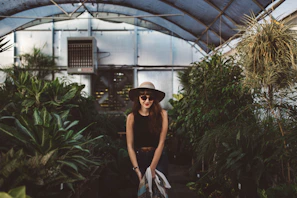 A model wearing a green verdevibe hat standing among tropical plants
