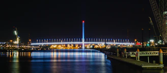 Night view of a well-lit bridge construction with cranes and scaffolding.