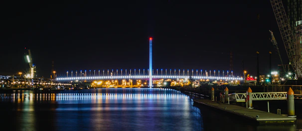 Night view of a well-lit bridge construction with cranes and scaffolding.