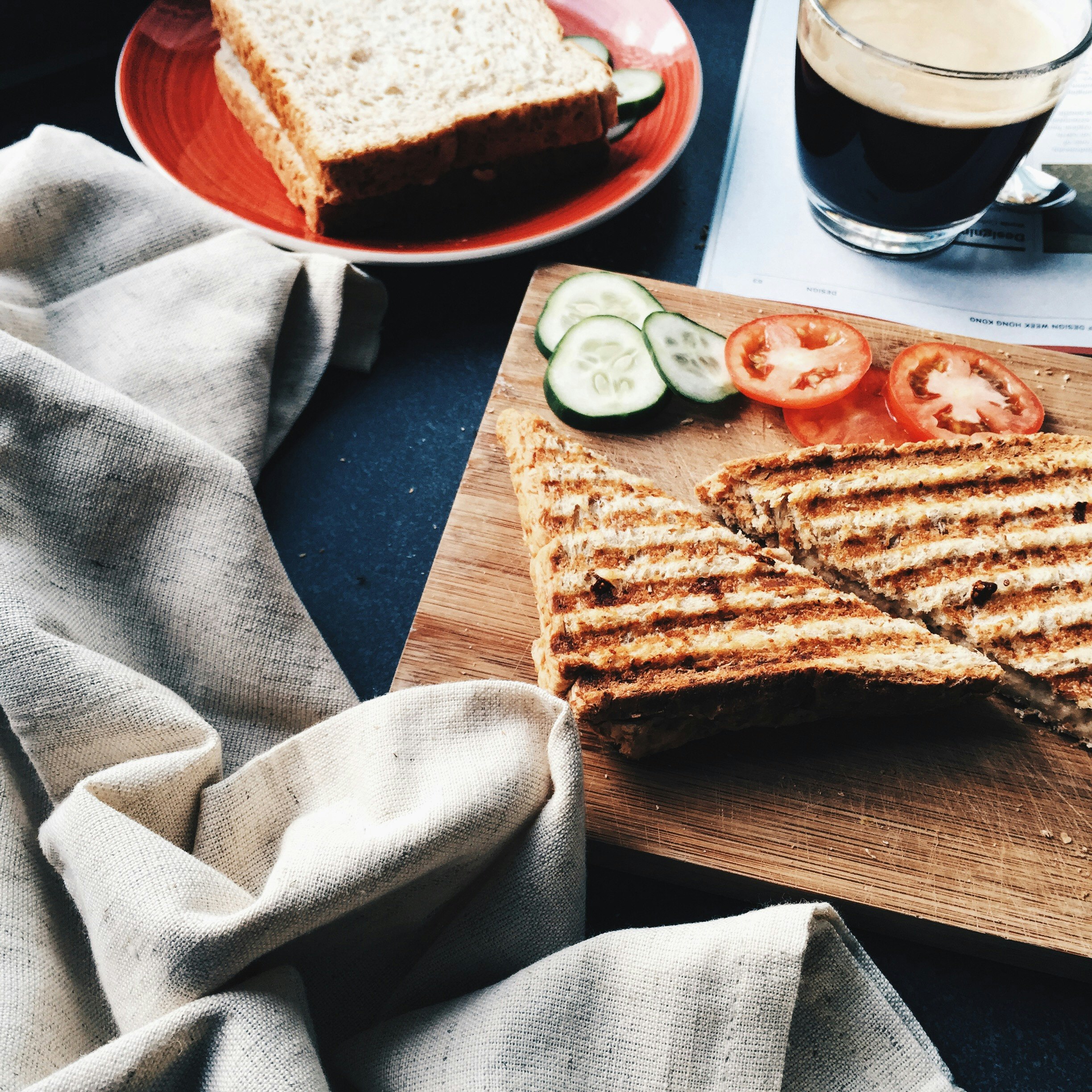 sliced grilled bread beside tomatoes and cucumbers on brown wooden board