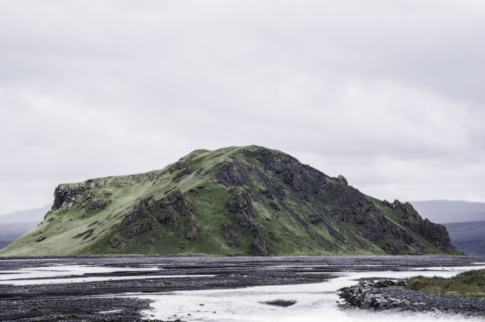 mountain beside sand with cloudy sky