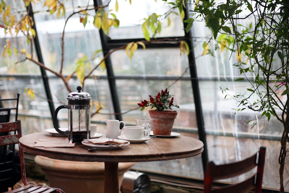 round brown wooden table with french press on top with white ceramic teacup beside