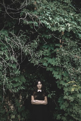 The model posing in a flowing dark green cloak, surrounded by ghostly white fog in the forest.