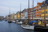 assorted-color boats beside assorted-color buildings at daytime