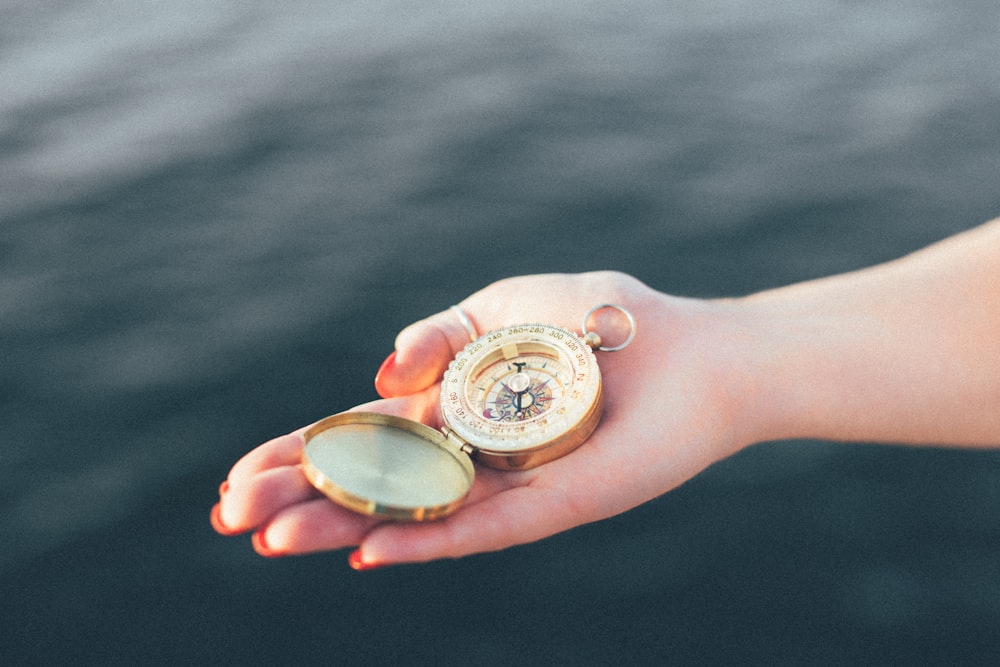 person holding gold-colored pocket watch