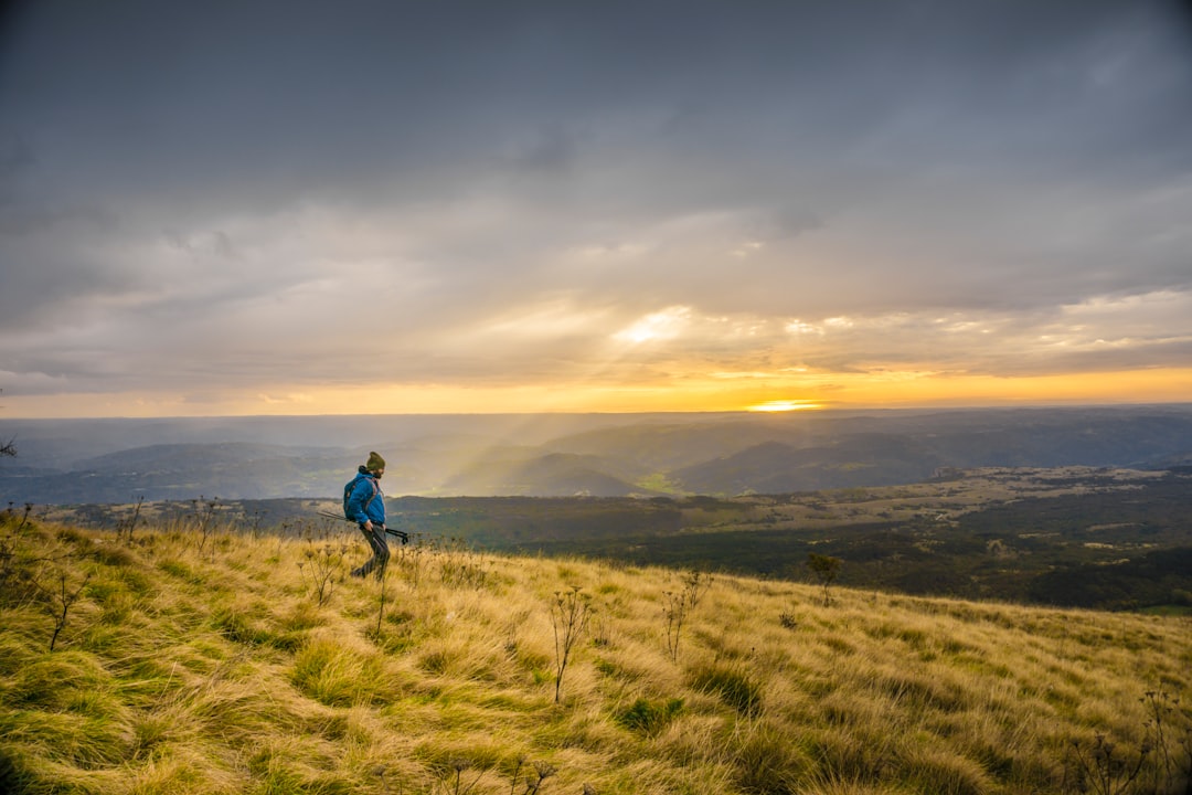 man in blue jacket walking on top of the mountain