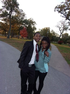 A stylish engagement photo of a couple laughing together on a cobblestone street lined with autumn leaves.