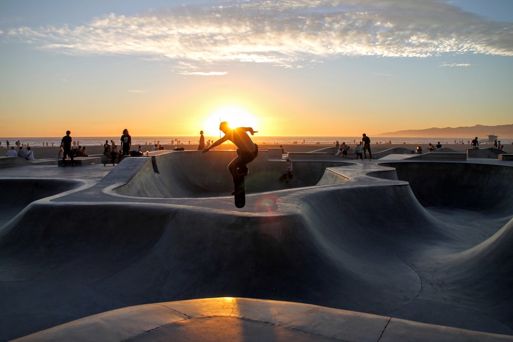 Foto de la silueta del hombre montando la patineta en el campo de la rampa de la patineta