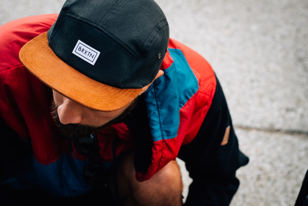 hombre con gorra Baxin negra y naranja mirando hacia abajo