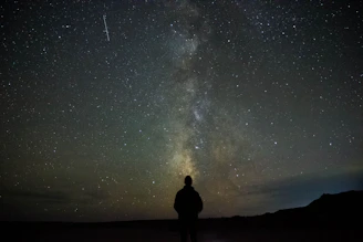 Silhouette of Mars glowing faintly behind the moon with a sparkling shooting star crossing the scene.