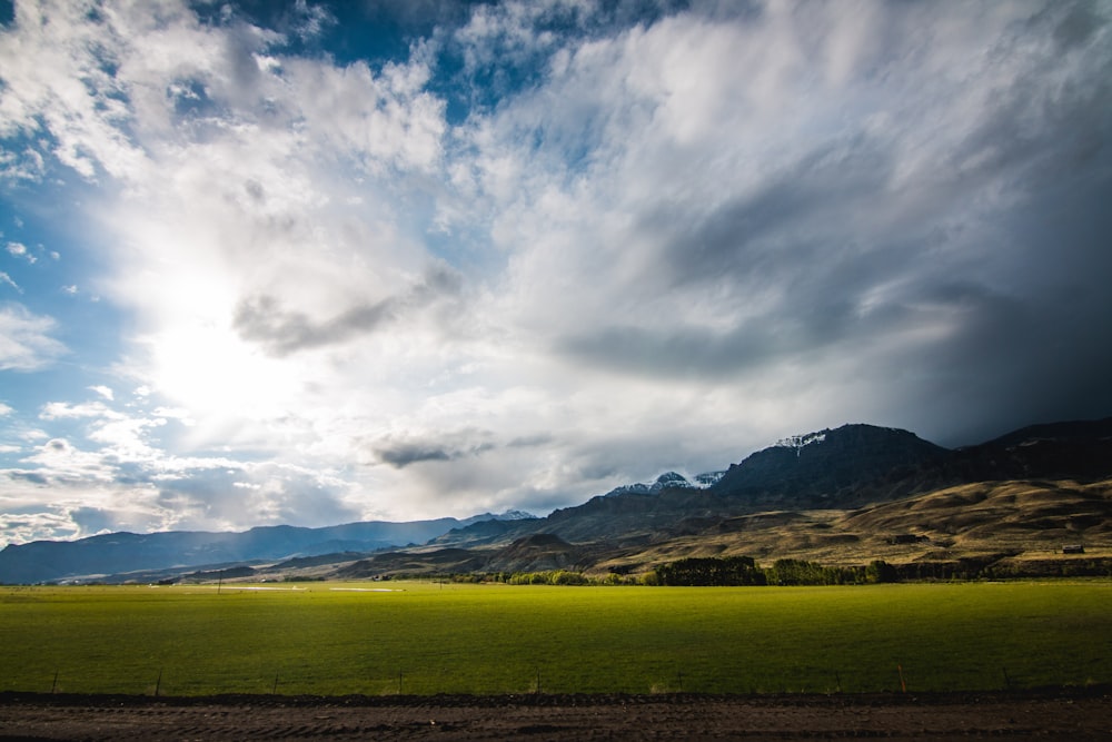 grass field under cloudy sky during daytime