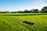 Close-up of a plot marker sign on a grassy field under a bright blue sky.