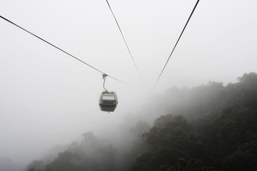 gray cable car over trees near mist