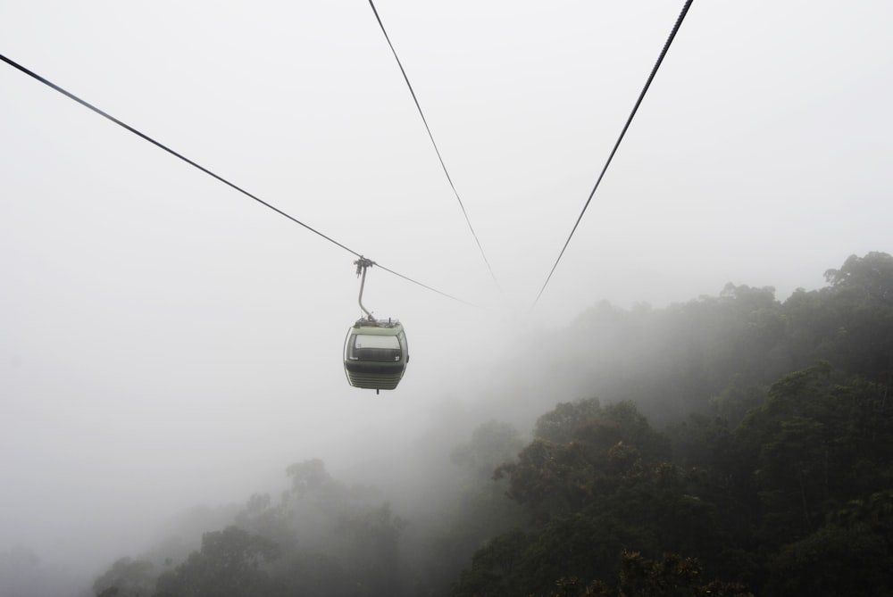 funivia grigia sopra gli alberi vicino alla nebbia