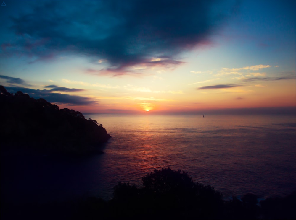 ocean and mountain under cloudy sky during golden hour