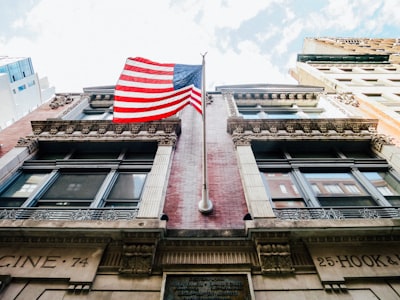 low angle photography of waving u.s.a. flag hang on bricks wall american zoom background