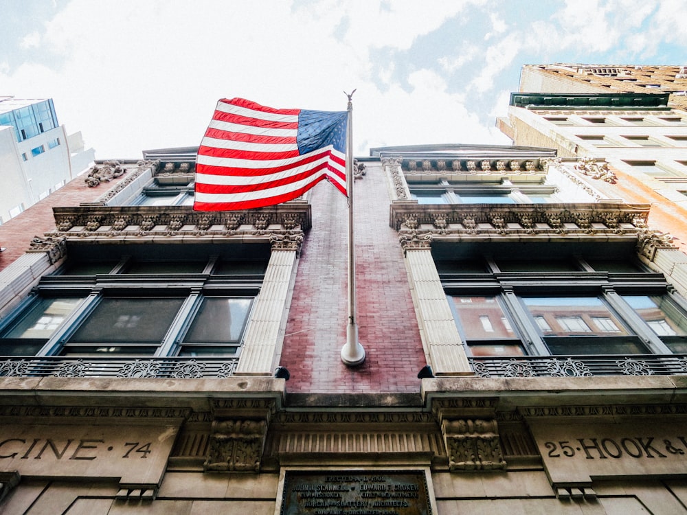 low angle photography of waving U.S.A. flag hang on bricks wall