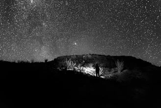 An immersive scene of a lone figure standing on a cliff under a vast cosmic sky, bathed in warm gold and amethyst light.