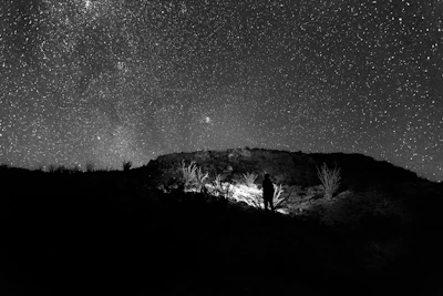 An immersive scene of a lone figure standing on a cliff under a vast cosmic sky, bathed in warm gold and amethyst light.