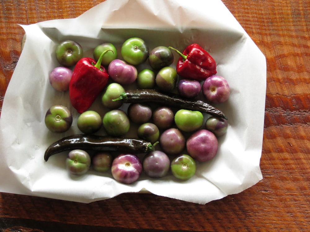 green and purple tomatoes and red bell peppers in white paper