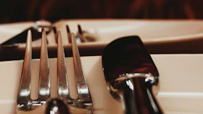 Close-up of a polished stainless steel cutlery set arranged neatly on a rustic wooden table.