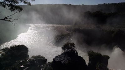 A misty morning view of a cascading Ourika Valley waterfall surrounded by lush greenery.