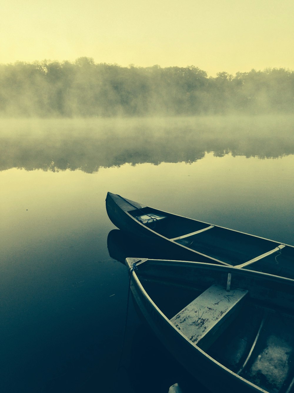 two gray canoes on misty body of water