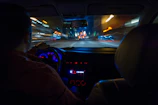 Night cityscape viewed from inside a moving car with glowing dashboard