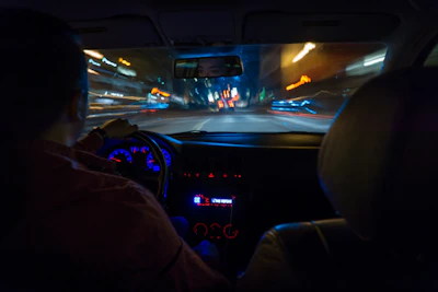 Night cityscape viewed from inside a moving car with glowing dashboard