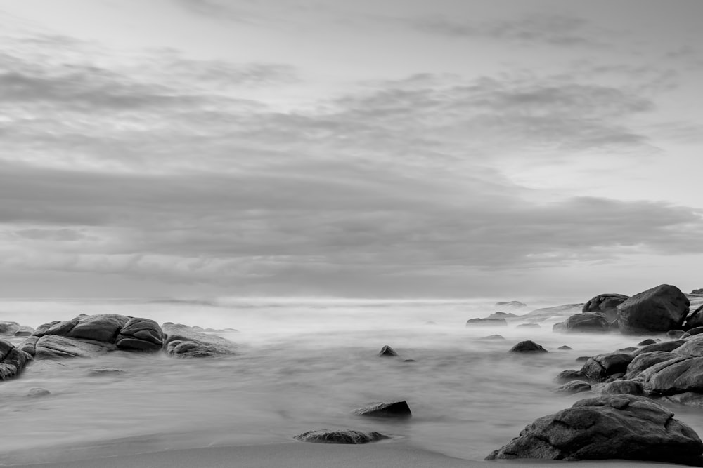 grayscale photo of rock formation surrounded with body of water