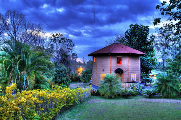 A cozy home surrounded by lush red sandalwood trees at sunset.