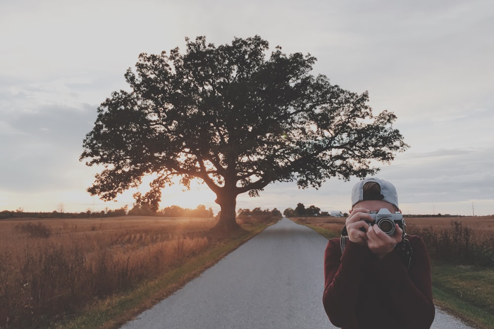 man taking photos using gray DSLR camera