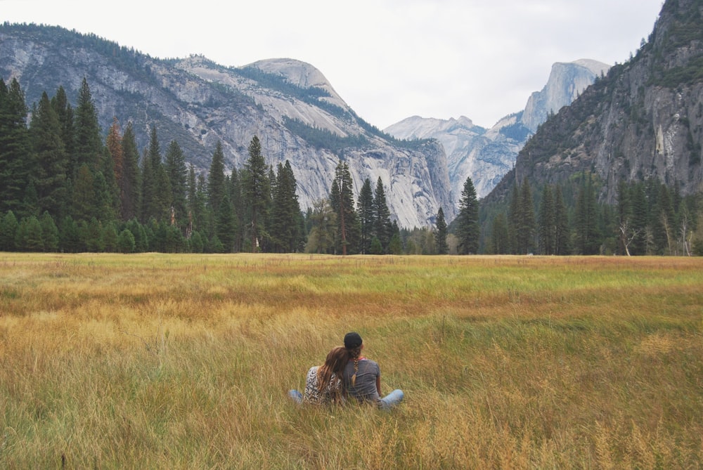 two person sitting on grass field