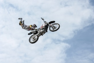 low angle photography of motocross player performing motocross flying style