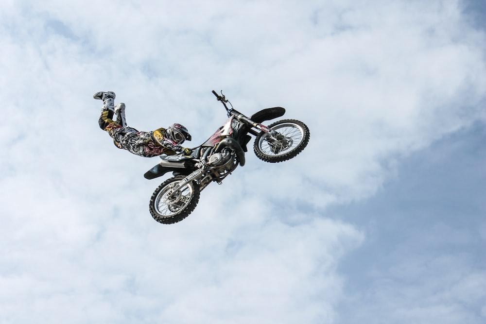 Fotografía de ángulo bajo de un jugador de motocross realizando un estilo de vuelo de motocross
