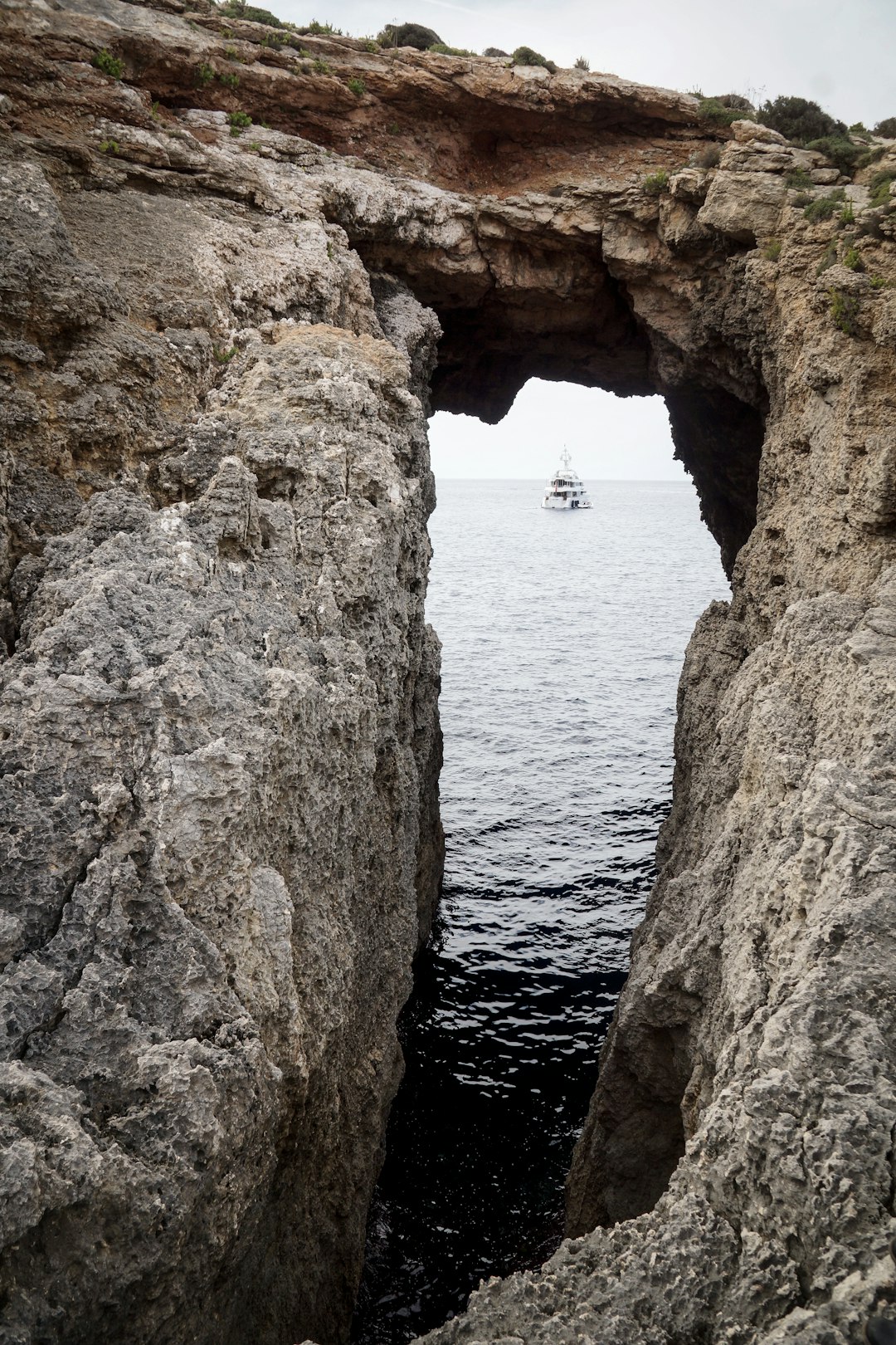 rock formation near sea with sailing ship