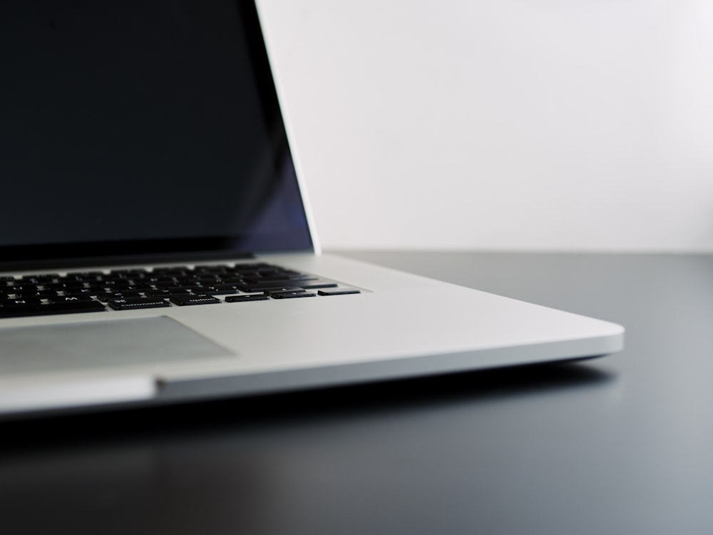 silver laptop computer on black table