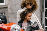 woman and girl showing their tongues beside motorcycle